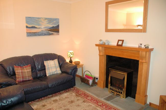 The sitting room in Bruaich Cottage, Lochcarron is cosy with a traditional fireplace and has splendid views.